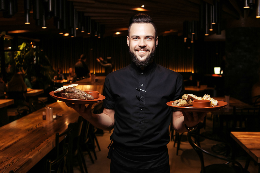 garçom servindo dois pratos em gastrobar