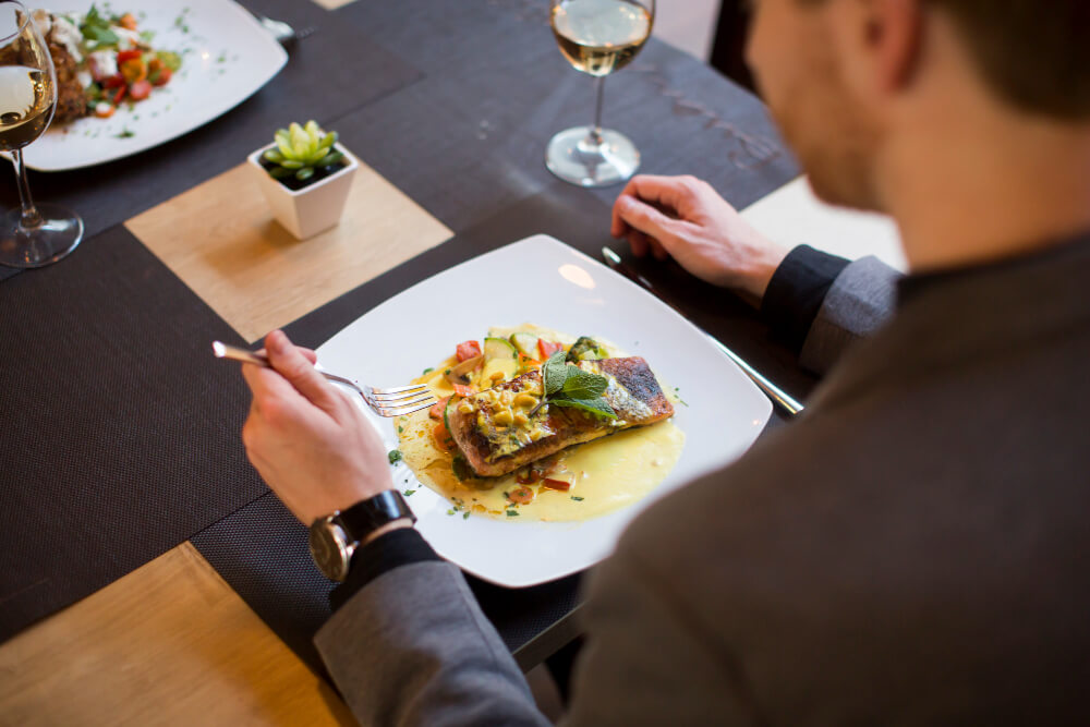 homem comendo salmão grelhado em restaurante a la carte