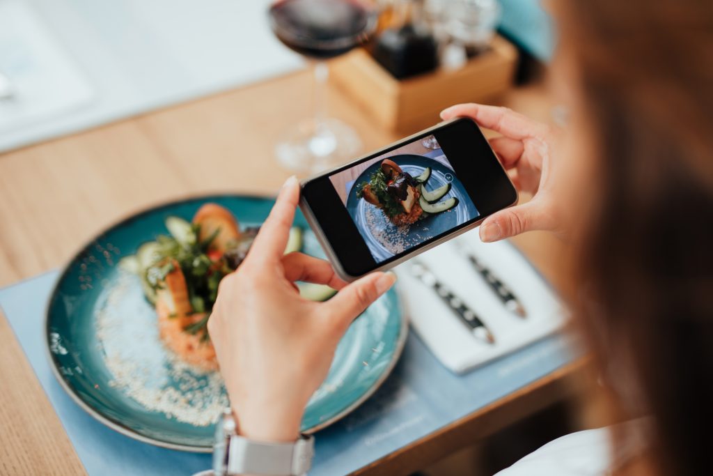 cliente tira foto do prato em restaurante para publicar no instagram