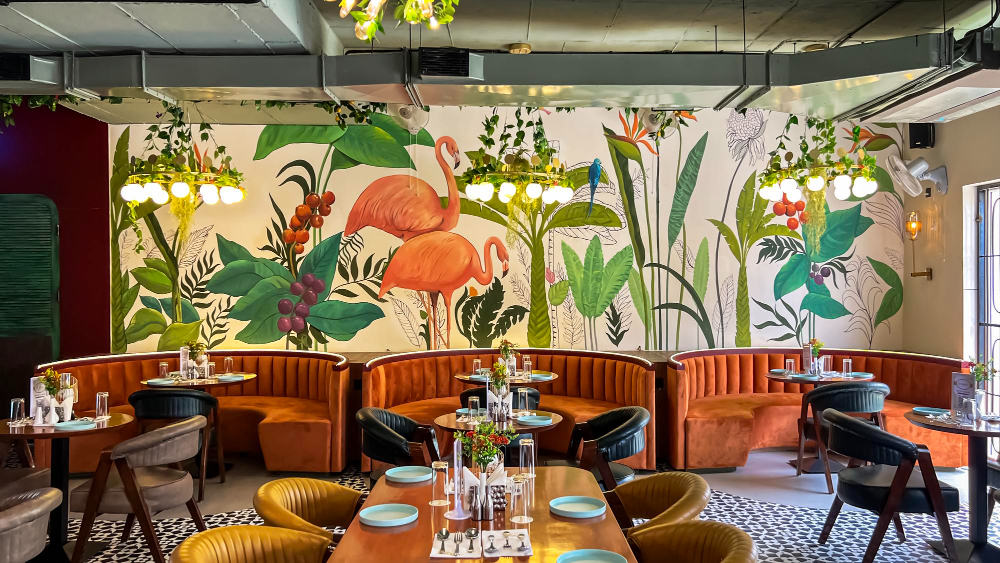 interior de restaurante com painel pintado de flamingos e folhagens na parede