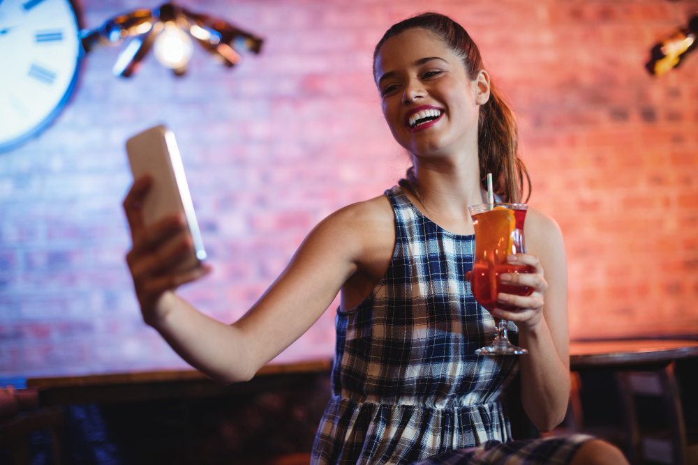 mulher tirando selfie em um bar com iluminação instagramável
