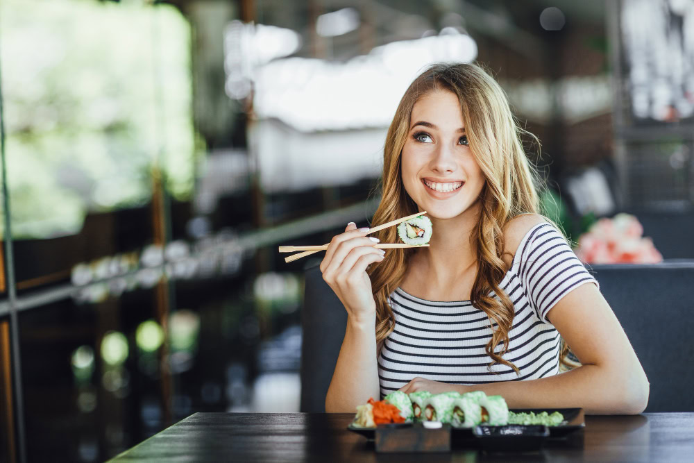 mulher em restaurante comendo um combo de sushi