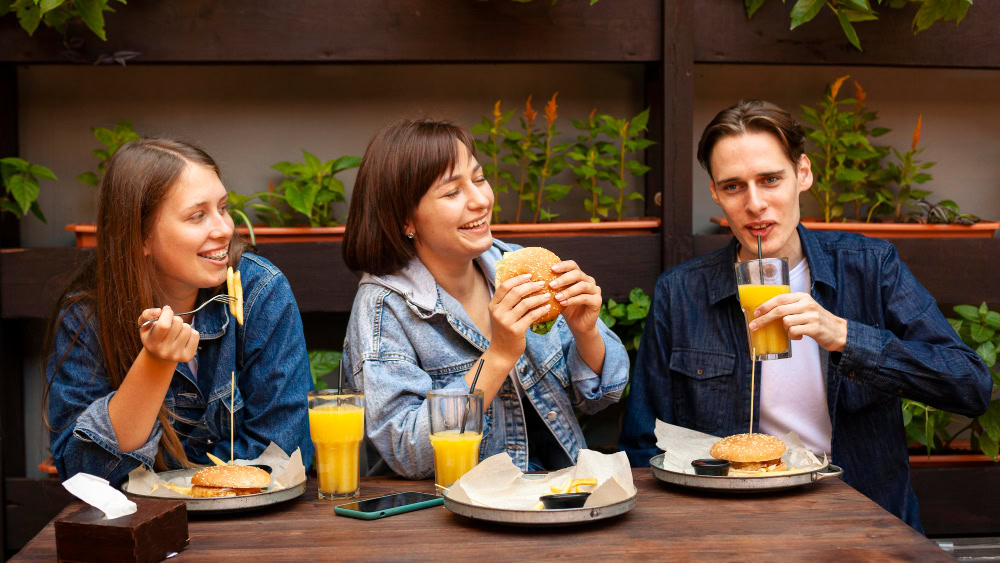 três amigos comendo combos de lanches