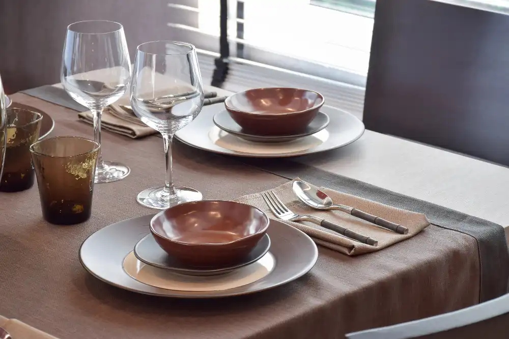 Mesa decorada com utensílios de serviço de restaurante, incluindo pratos, taças e talheres, ideal para jantares elegantes e eventos especiais.