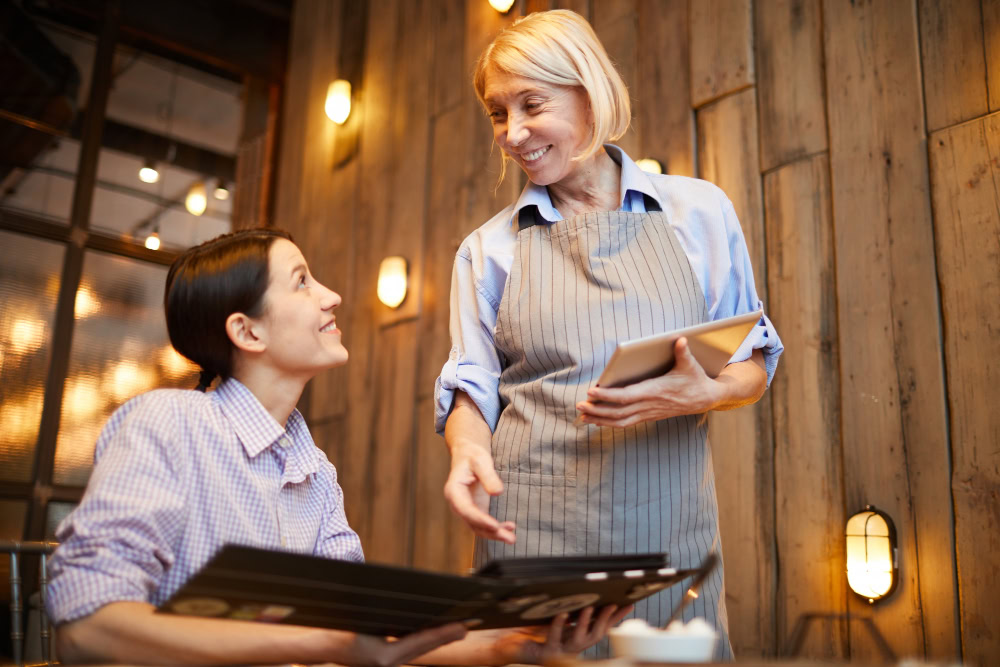 Garçonete freelancer falando sobre o cardápio para cliente em restaurante